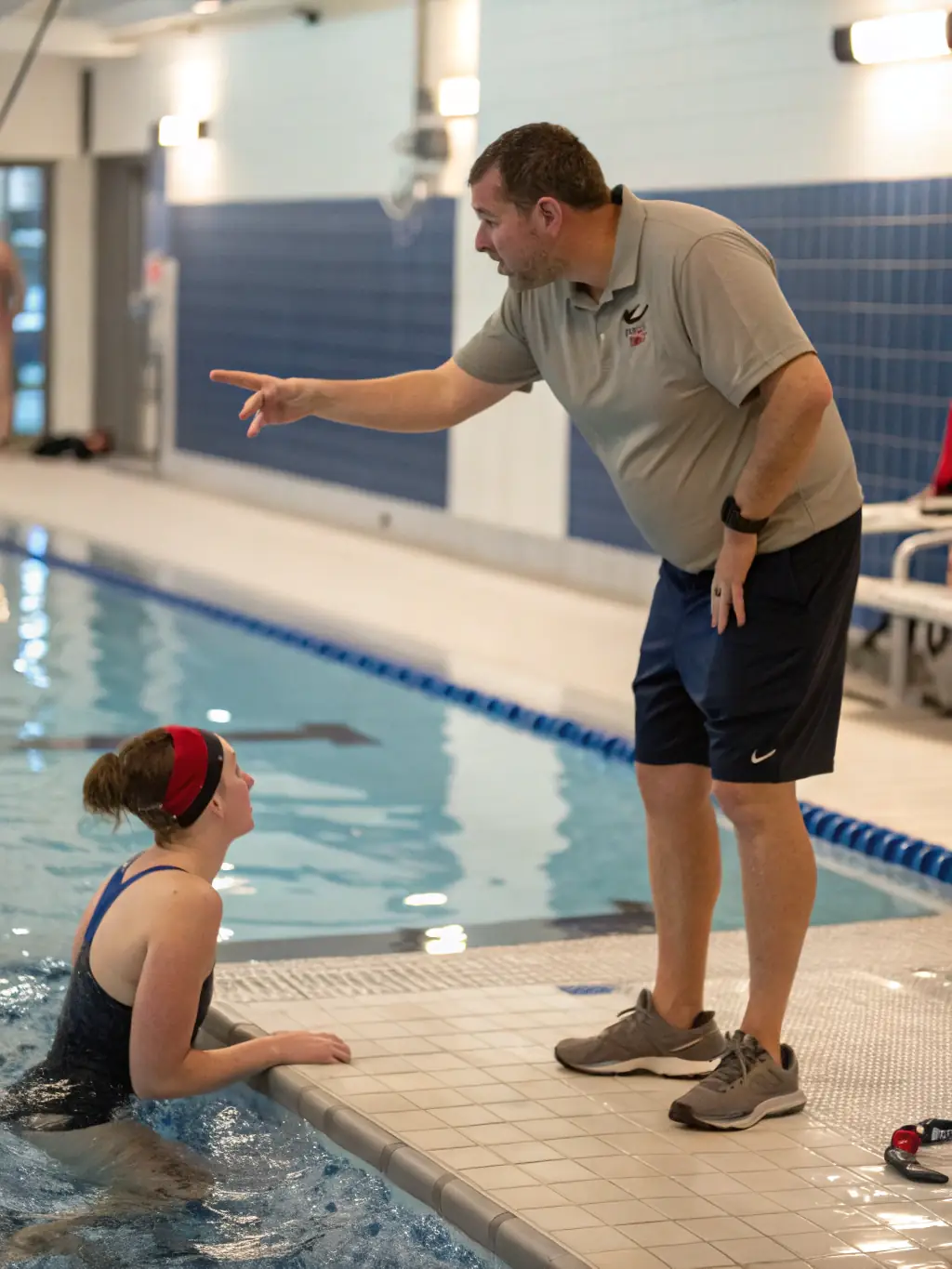 A focused image of a swim coach providing personalized instruction to a competitive swimmer at the AQUATIC CLUB, demonstrating the club's dedication to excellence.